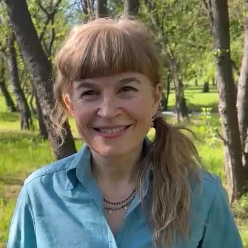 Dana Mărghidan, psychotherapist, smiling outdoors among trees